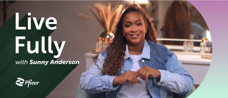 Smiling Sunny Anderson standing at a kitchen counter filled with food dishes